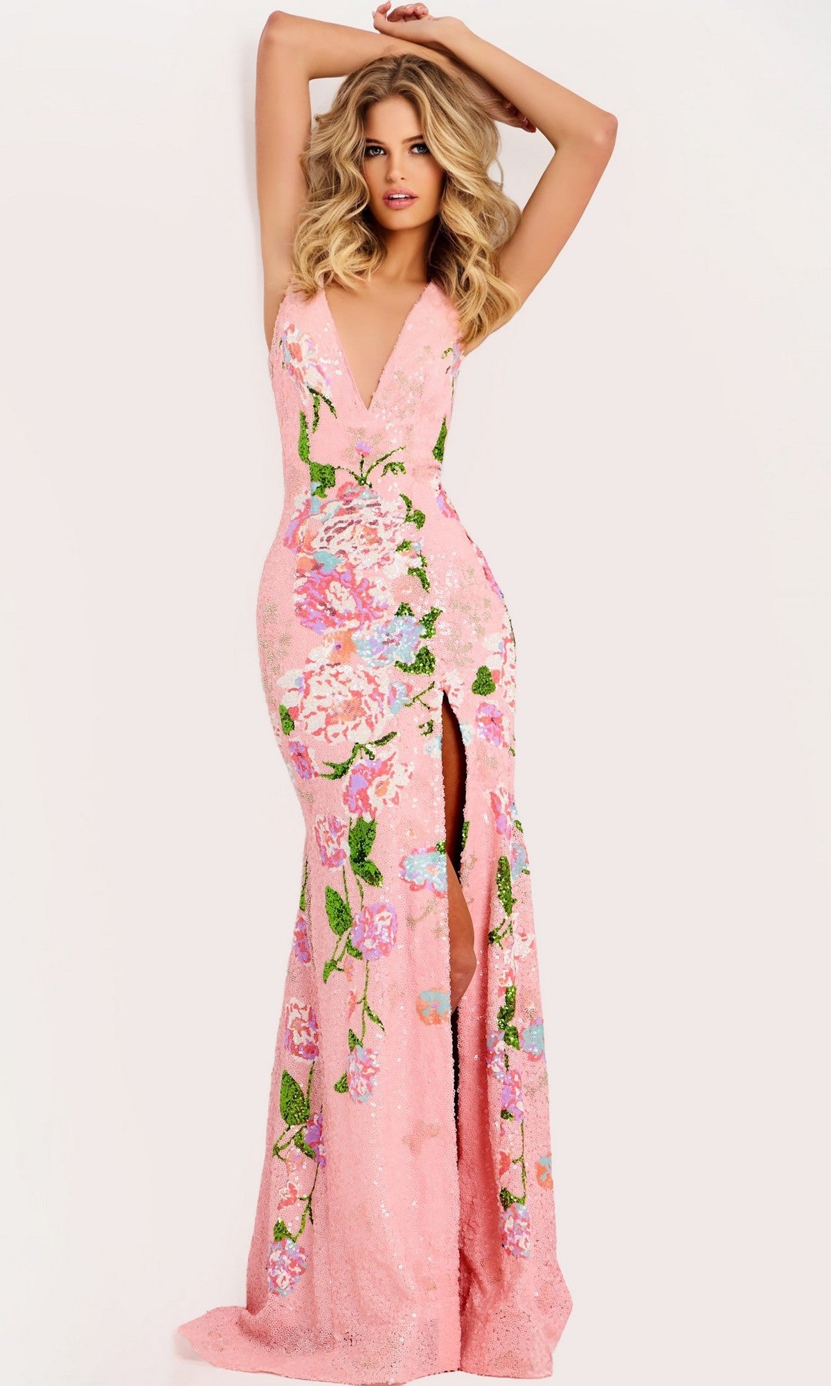 A woman stands against a plain background wearing the Jovani 48636 Long Prom Dress, a floor-length, sleeveless pink gown featuring a deep V-neck, beaded floral embroidery, and a high front slit.